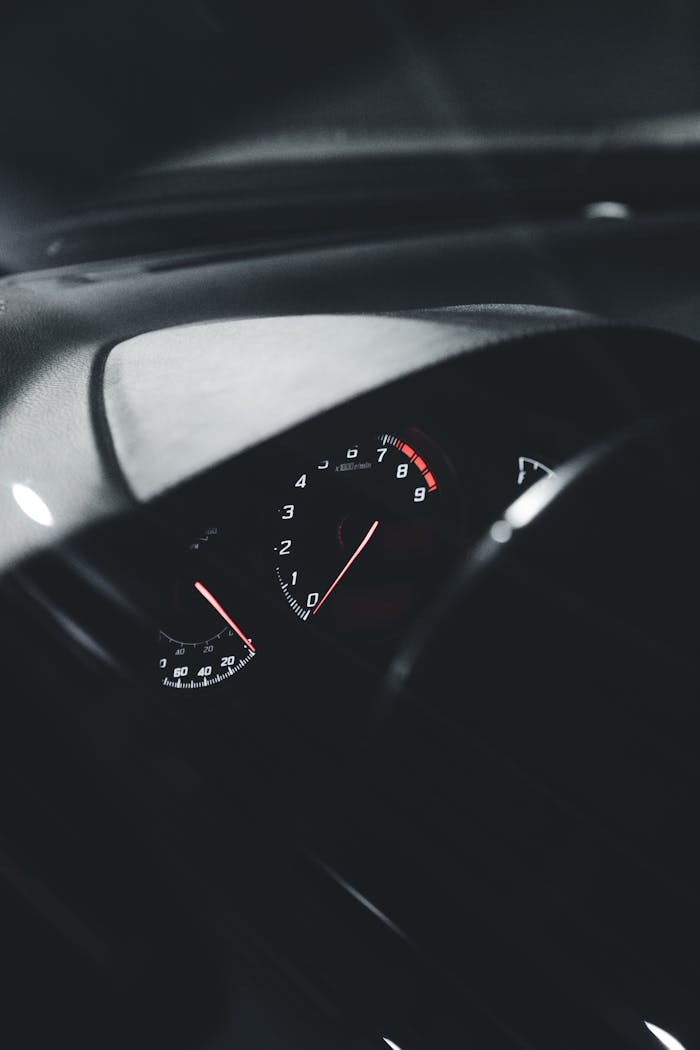 Close-up view of an illuminated car speedometer at night, showcasing sleek interior design.
